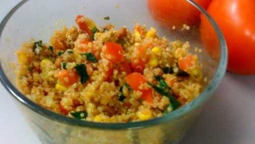 quinoa, beans, and veggies in a glass bowl with two tomatoes beside